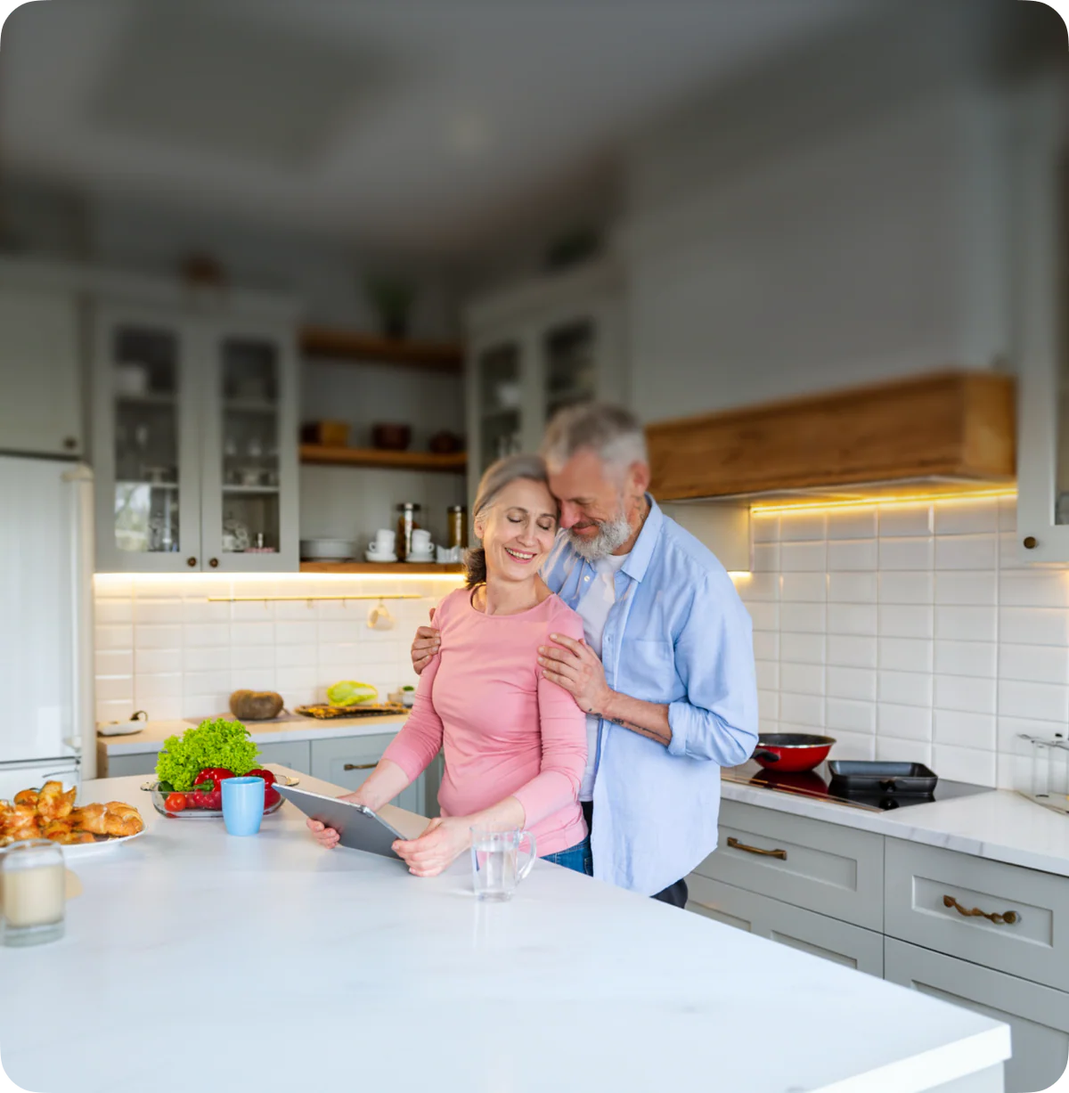 Couple in a modern kitchen using a tablet device.