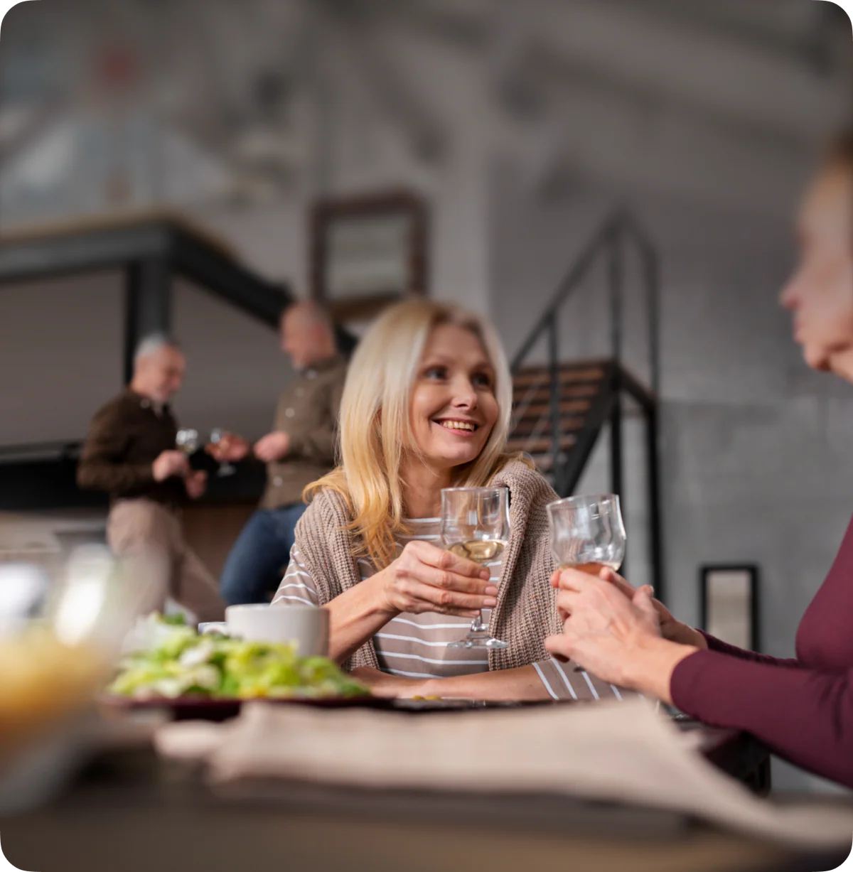 Two people sitting at a table with food and drinks, smiling.